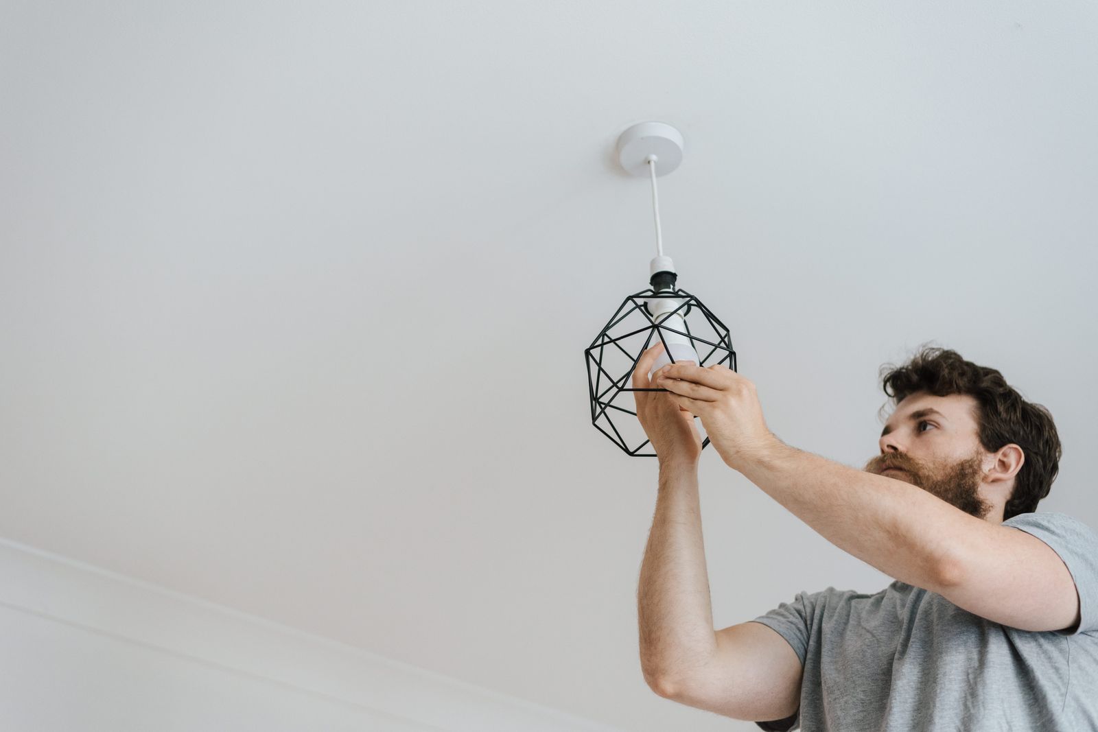 A light fixture being fitted and connected at the ceiling box.