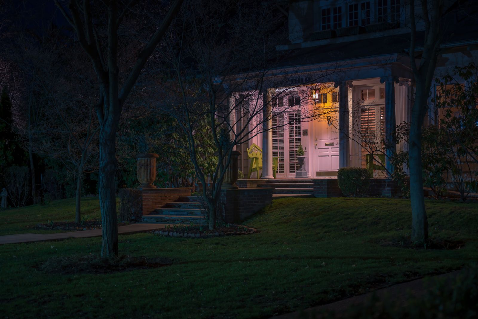 A suburban house exterior lit after dark by its outdoor lighting.