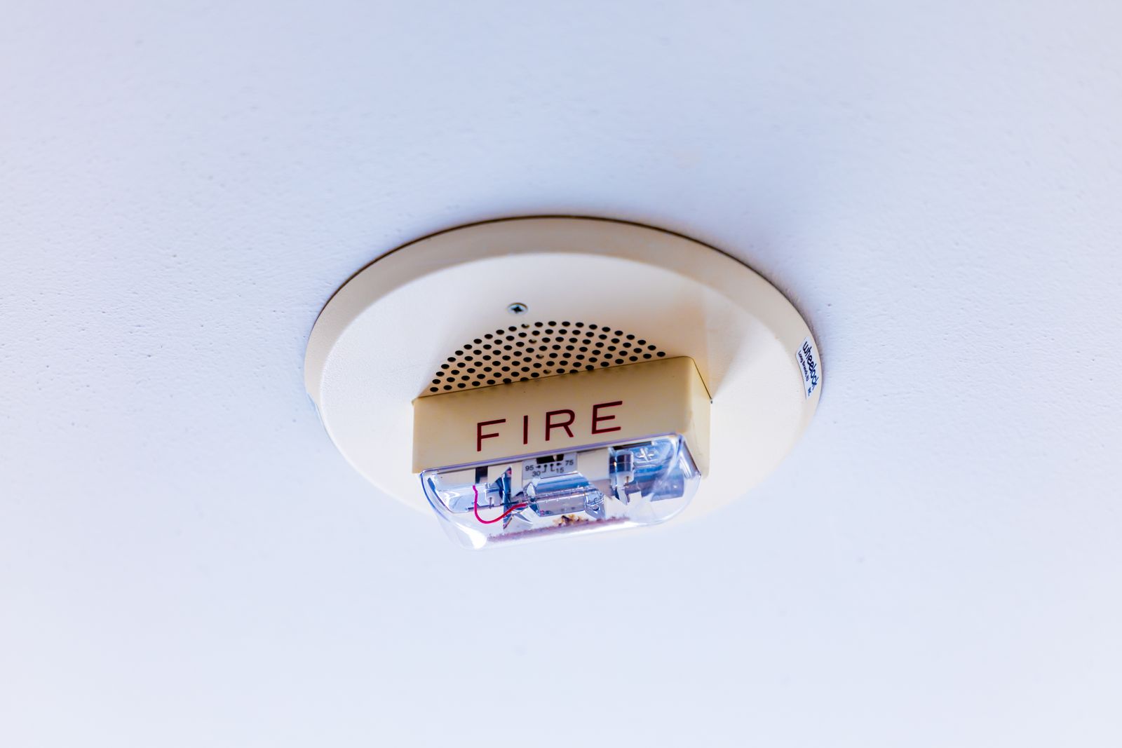 A ceiling-mounted smoke alarm of the type wired in during a detector installation.